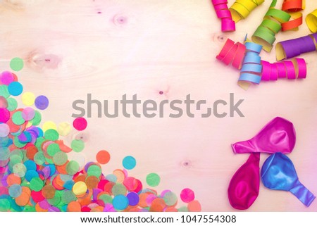 Colorful confetti and streamer as party decoration lying on wooden background with blank copyspace as flatlay