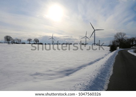 small road with fields of snow and windmills