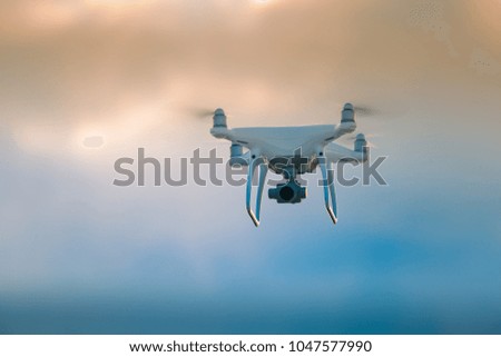 A beautiful flying drone in the evening skies. Aero photography in action. White drone flying.