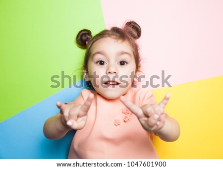 Pretty 4-year little girl with funny face on multicolor background. Bright colors and stylish picture.