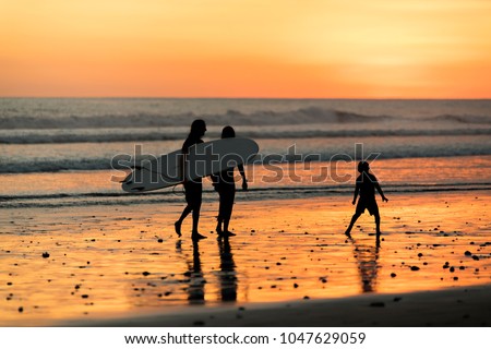 Happy family father, mother, son with fun along sunset sea surf on black
