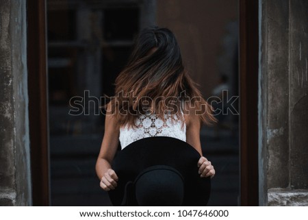 Girl winds her hair. Girl with a black cap.