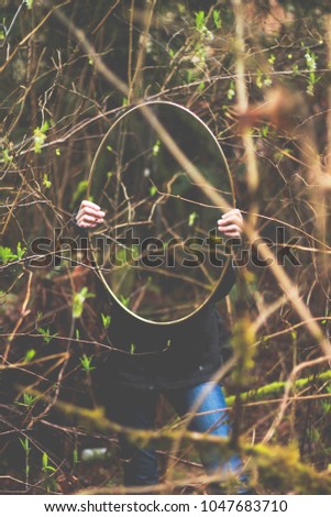 Girl holding mirror in the forest. 