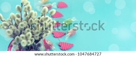 Banner Festive composition in a Glass vase with twigs catkins. Bright Candy garlands on a blue background.