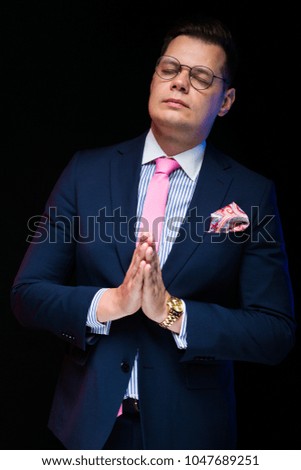 Portrait of confident handsome businessman showing sign meditate with closed eyes on black background