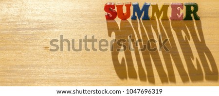 Colorful 'SUMMER' words with shadows under the morning lights on yellow table top