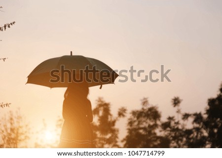 silhouette little girl under umbrella at sunset. 