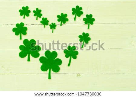 St Patricks Day shamrocks forming heart shape on wooden background