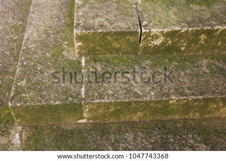 Close up outdoor perspective view of the corner of an ancient stone staircase located in a french city. Textured surface colored in grey and green by moss. Pattern of angular shapes. Abstract design.