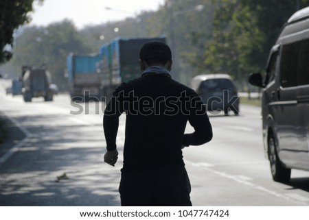 Men wear black hats and black long-sleeved shirts running forward during the day on highways with traffic and transportation on holiday.