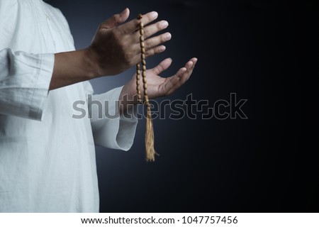 Hand of muslim people with praying gesture over dark background Royalty-Free Stock Photo #1047757456