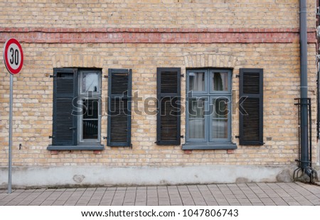 Historic wooden windows with shutters open. Shutters partly open on a brick building.