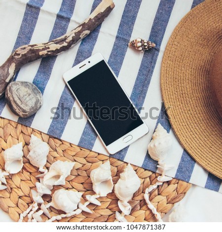 Summer holiday, vacation, relaxation concept. Straw hat, mobile phone, smartphone,  sea shell, rock,
snag.  Top view, flat lay on blue and white background.