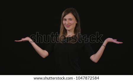 A beautiful young lady spreading her arms against a black background. Medium Shot