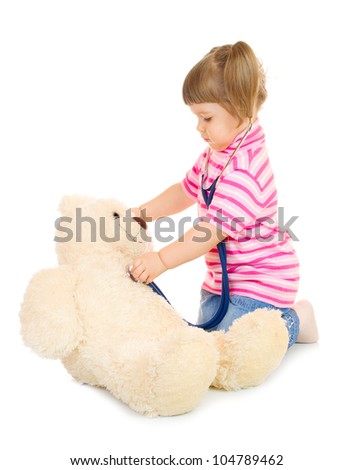 Little girl listens a stethoscope to a toy bear isolated