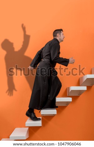 Priest climbing some stairs, and his shadow falling