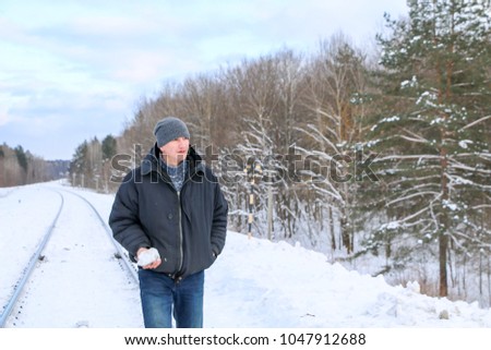 man goes by rail in winter.  guy is balancing on rails. travel, adventure, walk, hitchhiking.
