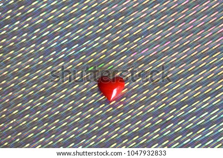Red marble love heart stone set against a holographic silver rainbow paper background