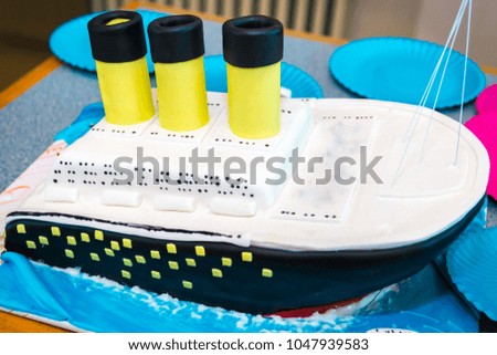 Children's fondant ship birthday cake with three yellow funnels on the table in restaurant. Copy space.