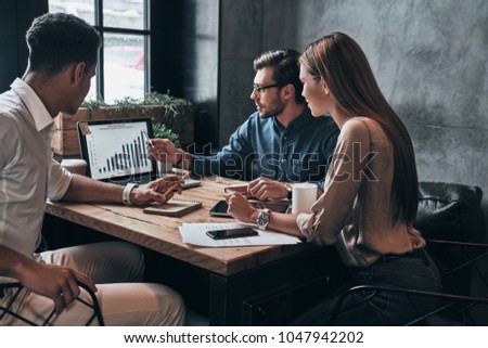 Business professionals. Group of young confident business people analyzing data using computer while spending time in the office Royalty-Free Stock Photo #1047942202