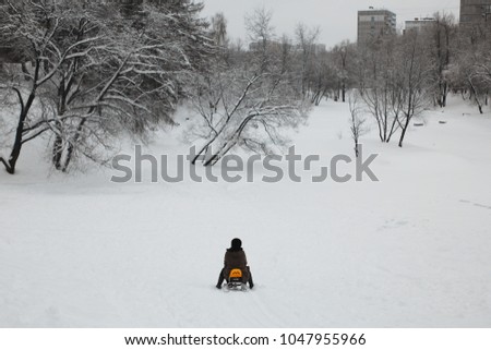 A parent and a kid are riding snow racer with taxi design/sign in Moscow residential area, Russia. World snow day. Copy space for information. 