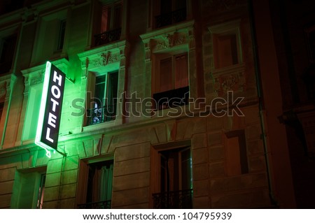 Illuminated green hotel sign on building. Paris, France, Europe.