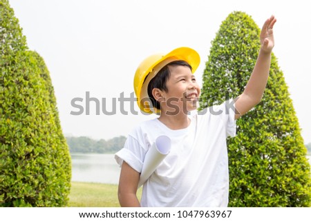 Asian boy in white t-shirt with yellow helmet dress like engineer with garden scene
