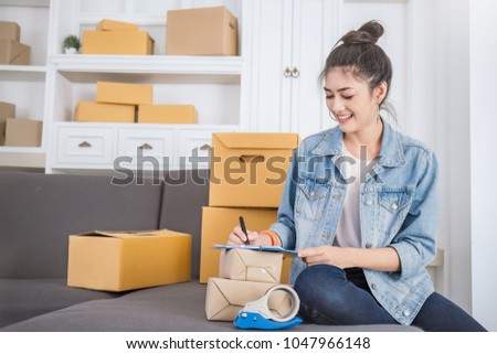 Startup small business entrepreneur SME, asian woman writing address on clipboard box. Portrait of young Asian small business owner, online marketing packing delivery warehouse, SME e-commerce concept