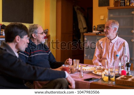 Three older men talking eating and drinking