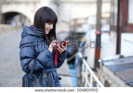Happy beautiful brunette tourist in Paris sending an sms to a friend