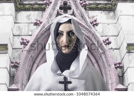 A beautiful nun in white hooded cloak with cross on her neck standing on temple background. 