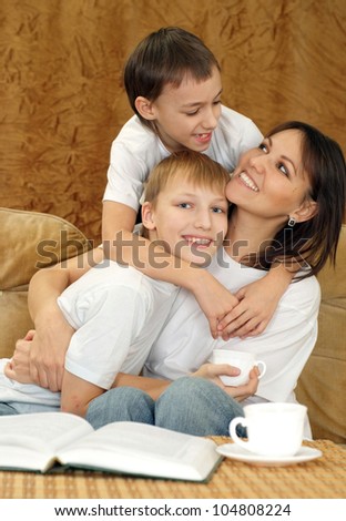 Beautiful charming mummy and sons sitting on a brown background