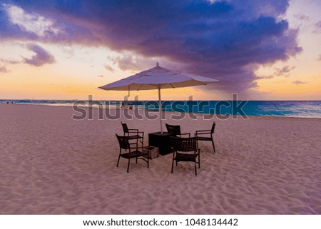 dream beach at sunset on the Caribbean sea with palm trees and chairs on the island of Aruba in the Dutch Antilles "Eagle Beach"