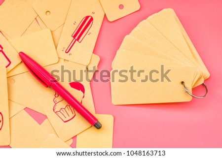 set of recycled label tags tied with a metal ring to a notepad with cute pink drawings and pink liner or pen on pink background