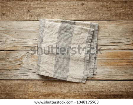 folded linen napkin on old wooden table, top view