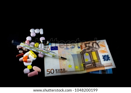 Colored pills, thermometer and euro bills on black backround