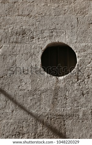 Close up outdoor view of a concrete wall with a round hole and a shadow line. Geometric image with a black circle and an grey oblique line. Abstract architectural picture of a detail facade building.
