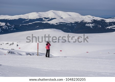 Tourist taking a phone picture of mountain winter landscape