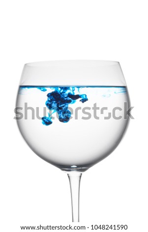 Food coloring diffuse in water inside wine glass area for slogan or advertising text message, on isolated white background.