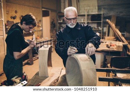 Two master carpenters working together in their woodwork or workshop. Royalty-Free Stock Photo #1048251910