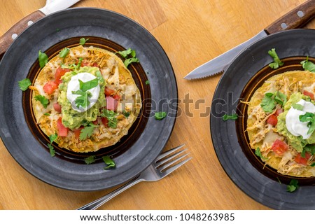 Chicken tostadas top view. Tostadas are a type mexican food, made with crispy fried corn tortillas covered with layers of various ingredients such as chicken, guacamole, cheese, sour cream & salsa.