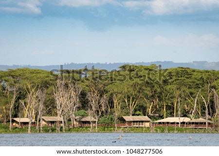 Bungalows on lake in kenya, Africa. Tourist villas by the water with trees in the background African cabanas.