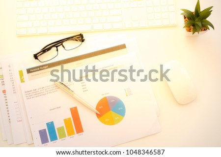 White Workspace with keyboard  and chart with golden light