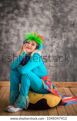 Young cheerful girl in a bright pony horse costume on grey background. Animator, costume show, a carnival. Bright image for the poster, bright cheerful card. Carnival costume, brightly colored wig.