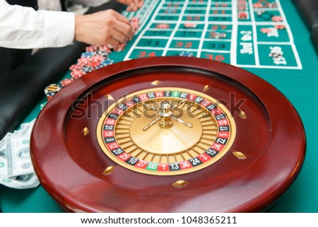 Roulette for playing poker on the table background with players.