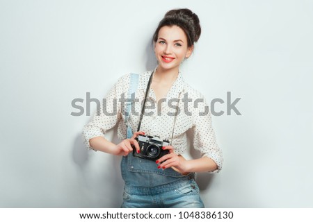 Fashion look, pretty cool young woman model with retro camera wearing in denim clothes posing on white wall. Expressive beauty girl photographer holding photocam. Emotions Lifestyle People concepts