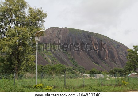 Zuma Rock, a large monolith, an igneous intrusion composed of gabbro and granodiorite, located in Niger State, Nigeria, near the capital Abuja.  Royalty-Free Stock Photo #1048397401