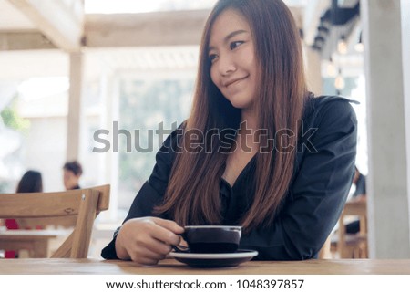 Closeup image of a beautiful asian woman holding and drinking coffee with feeling relaxed in cafe