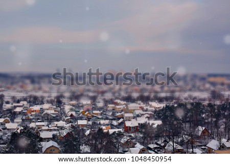 landscape with miniature houses with snowy rooftops, tilt shift effect and blue skies