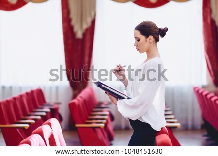 girl with pen in her hand watches documents in hall